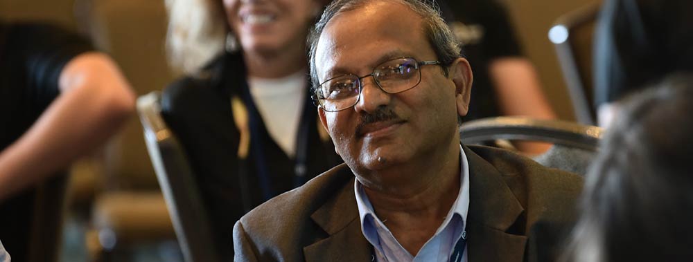 Male conference attendee wearing glasses and brown blazer.